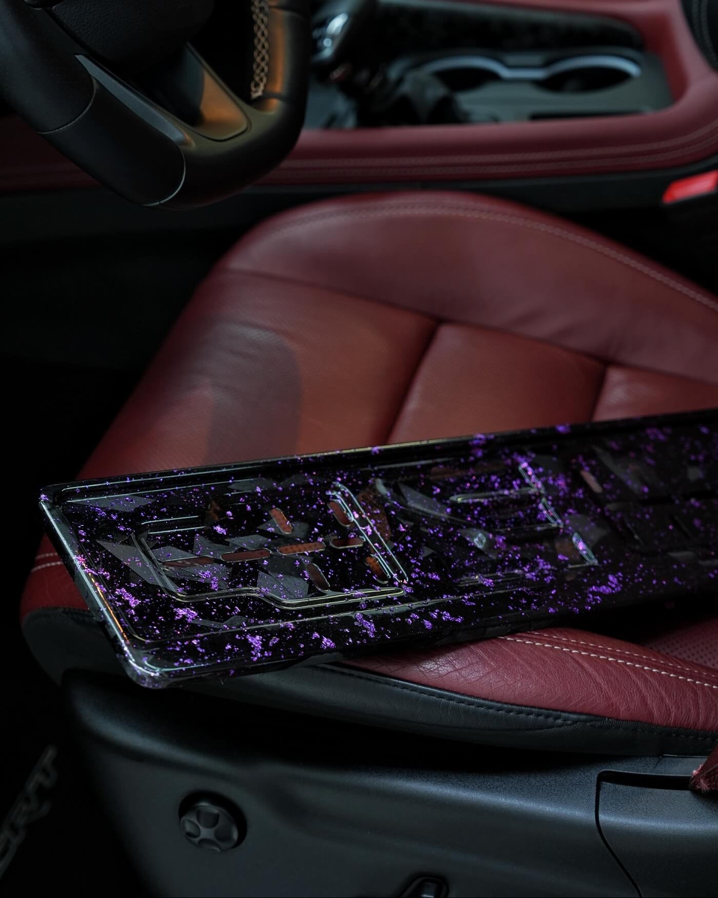 Car interior with a purple and black license plate on a red seat